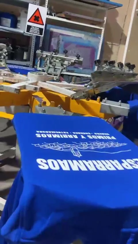 Proceso real de serigrafía en taller sobre una sudadera azul